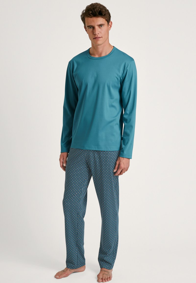 Turquoise long-sleeve top paired with patterned blue pajama pants. Fabric is smooth, with a fitted design and elastic waistband.
