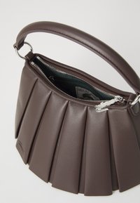 Geantă de piele maro cu design pliat, detalii cu fermoar argintiu și căptușeală interioară verde, având un mâner rotund și accente din metal.