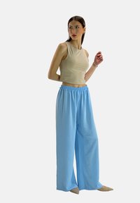 Beige crop top met mouwloos ontwerp, gecombineerd met losse, lichtblauwe, elastische taille brede pijpen. Gladde stof en natuurlijke val.