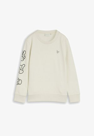 Kremowa bluza z długim rękawem, okrągłym dekoltem, małą grafiką ręki na piersi oraz trzema większymi czarnymi grafikami rąk na lewym rękawie.