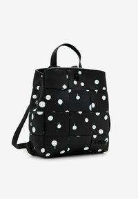 Mustasid kudumiga seljakott, millel on valged värviplekid, ülemine käepide, reguleeritavad õlarihmad ja väike esine logo silt.