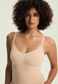 Nude camisole top with adjustable straps, seamless design, and gathered detail at the front. Soft, stretchy fabric for comfort.