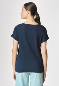 T-shirt blu navy a maniche corte con vestibilità rilassata, con risvolti e scollatura ampia. Design semplice, realizzato in tessuto morbido.