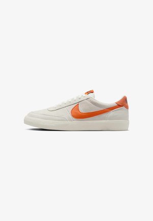 Zapatillas deportivas de ante blanco con el logo Nike Swoosh en naranja, cordones planos blancos y un collar acolchado. Suela de goma con acabado texturizado.