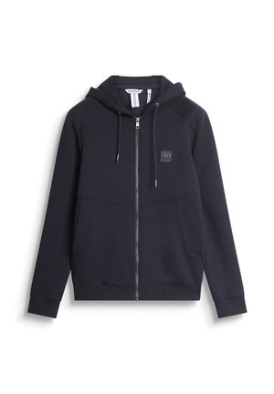 Tamno plava zip-up dukserica napravljena od mekog materijala, sa kapuljačom na vezanje, prednjim džepovima i malim logotipom na grudima.