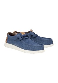 Scarpe di tela blu con suole in gomma bianca maculata, forma arrotondata, dettagli marroni e lacci per una vestibilità sicura. La texture appare morbida e resistente.