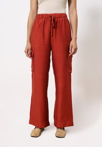 Wijde broek in een gestructureerde, dieprode stof. Voorzien van een elastische tailleband met een gestrikt koord en twee zijzakken.