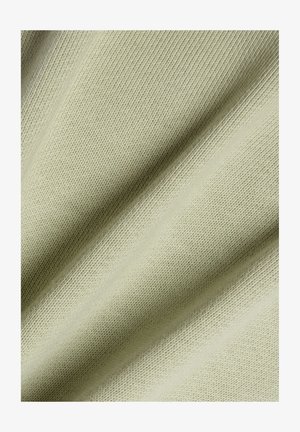 Lysebeige strikket stof med glat, fin tekstur vist i nærbillede med bløde folder, der skaber blide skygger.