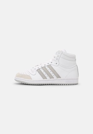 Hvid Adidas high-top sneaker med grå striber og beige tå-indsats, vist i sideprofil på en ensartet lys baggrund.