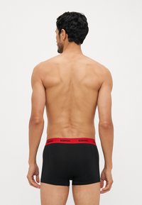 Schwarze Boxershorts mit rohem elastischem Bund, mit dem 'DIESEL'-Logo. Glatte Textur, enganliegendes Design, Schnitt über dem Oberschenkel.