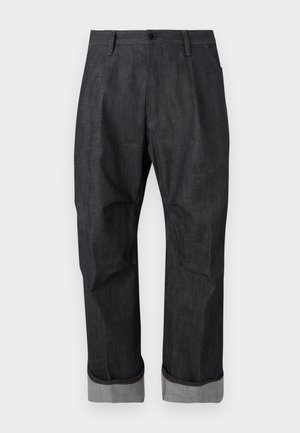 Tumši džinsu bikses ar aprocēm apakšā, priekšā ar pogu un rāvējslēdzēju, jostu cilpiņām un smalkiem izšuvumiem.