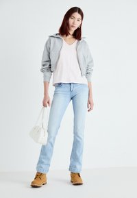 Gray cropped sweatshirt, pink striped v-neck shirt, light blue jeans, tan boots, white handbag. Smooth fabric and relaxed fit.