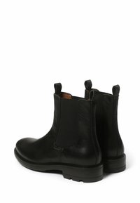 Bottes Chelsea en cuir noir avec panneaux latéraux en élastique, tirettes et semelle texturée. Bout arrondi et finition lisse.