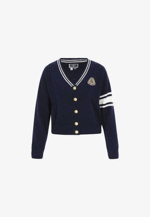 Tengerészkék kötött kardigán V-nyakkal, arany gombokkal és kötött mintázattal. Fehér csíkok találhatók az ujjakon és hímzett embléma díszíti.