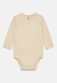 Ribbet langermet bodysuit i myk beige med omslagstdesign og trykknapper nederst og mansjetter på armene.