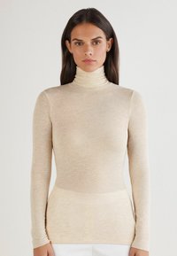 Beżowy golf z długimi rękawami, gładka tekstura, dopasowany krój, z wysokim kołnierzem i minimalistycznym wzornictwem, idealny do noszenia w warstwach.