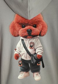Sudadera gris con un gráfico de perro de felpa que tiene una cabeza roja peluda, un suéter, pantalones negros y zapatillas. Los accesorios incluyen un bolso de hombro.