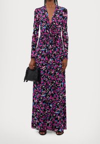 Maxiklänning med lång ärm som har ett svart tyg med ett livfullt blommönster i rosa, blått och vitt, cinchad midja och djup V-ringning.