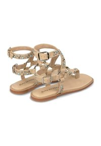 Sandali beige con più cinturini caratterizzati da un design decorativo di borchie argentate e accenti blu. Suola piatta e fibbie argentate.