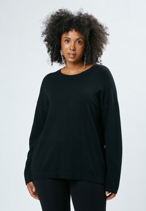 Schwarzer oversized Pullover mit Rundhalsausschnitt, langen Ärmeln und strukturiertem Stoff, der eine Nahtdetail an der Vorderseite aufweist.