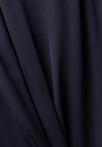 Mörkblått tyg med en slät textur och draperade veck, som visar subtil glans och mjukhet. Lämpligt för kläder eller stoppning.