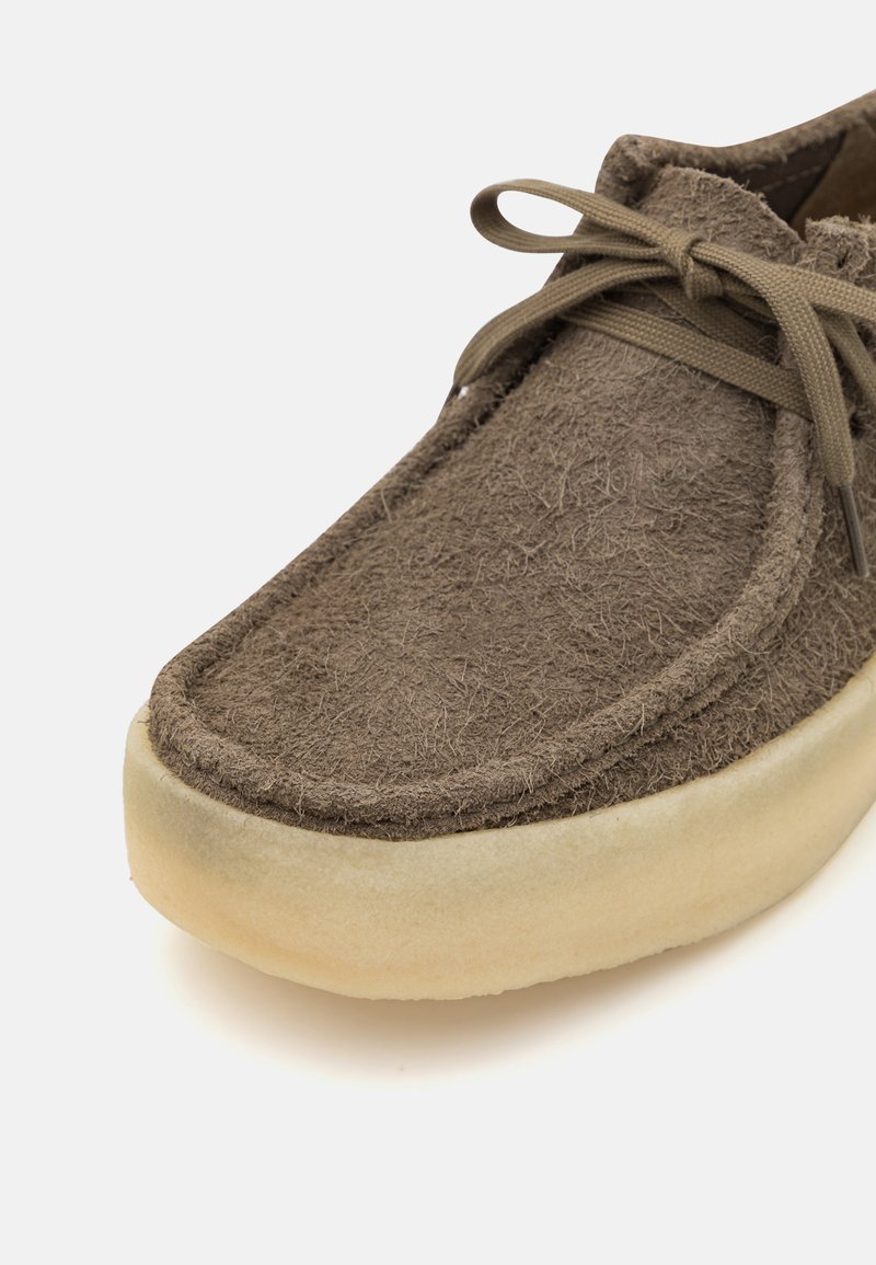Chaussure en daim marron avec dessus texturé et bout rond. Présente un lacet ton sur ton et une semelle en caoutchouc de couleur claire. Détails de couture subtils le long des bords.