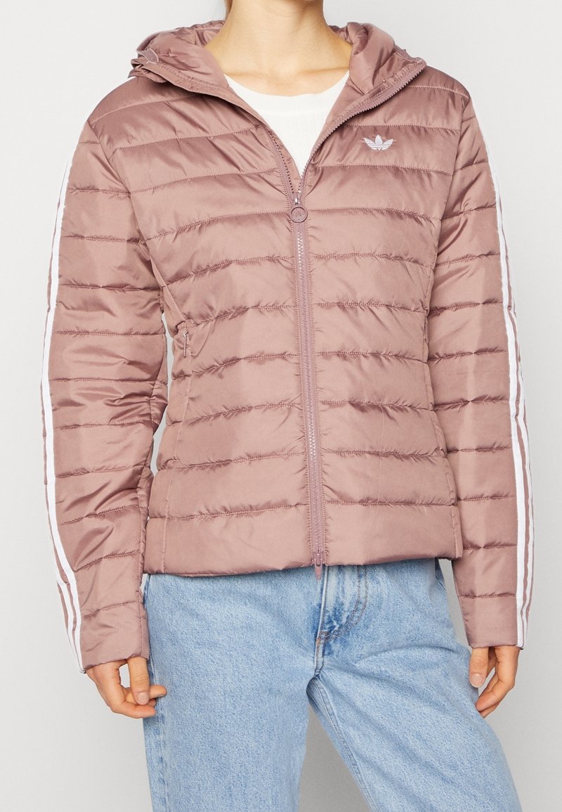 Izolowana kurtka zapinana na zamek w jasnym mauve z kapturem i białymi paskami po bokach. Charakteryzuje się lekko błyszczącą teksturą i pikowanym wzorem.