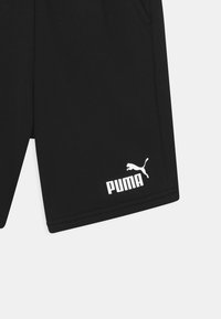 Pantalones cortos deportivos negros hechos de tela suave, con bolsillos laterales y un logotipo blanco de Puma con un motivo de gato saltando cerca del dobladillo.
