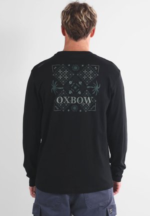T-shirt noir à manches longues avec un graphique décoratif au dos, portant le texte "OXBOW" imprimé en blanc et des motifs complexes en bleu sarcelle.