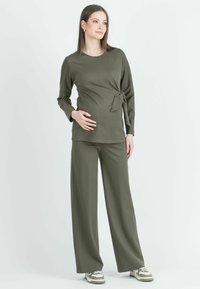 Olivgrünes Zweiteiler-Outfit mit einem langärmligen Wickeloberteil mit Seitenband und weit geschnittenen Hosen aus einem weichen, dehnbaren Stoff.