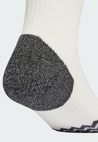 Calzino bianco con una sezione del tallone nera e testurizzata, caratterizzato da un design a coste e modelli sottili lungo il bordo e la suola per una migliore aderenza.