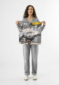 Zijden sjaal met een grijs, geel en zwart ontwerp, voorzien van illustraties van bergen, een auto en de stad. De randen zijn afgewerkt met een gerafeld trim.