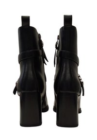 Stivali neri in pelle fino alla caviglia con tacco quadrato, caratterizzati da cinturini e accenti in metallo argentato, texture liscia e design elegante.