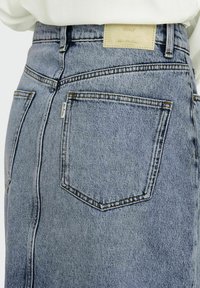 Falda de mezclilla azul con cintura alta, un leve desgastado y bolsillos traseros. Incluye una etiqueta con "ONLY" cosida cerca de la cinturilla.