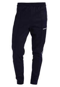 Marinblå Adidas träningsbyxor med elastiskt midjeband, dragkedjefickor på sidorna och vit logotyp och ränder längs sidorna.