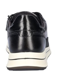 Baskets noires avec un dos en cuir brillant, des côtés en tissu texturé, une semelle intermédiaire blanche et une semelle extérieure en caoutchouc plate. Détail de fermeture éclair sur le talon.