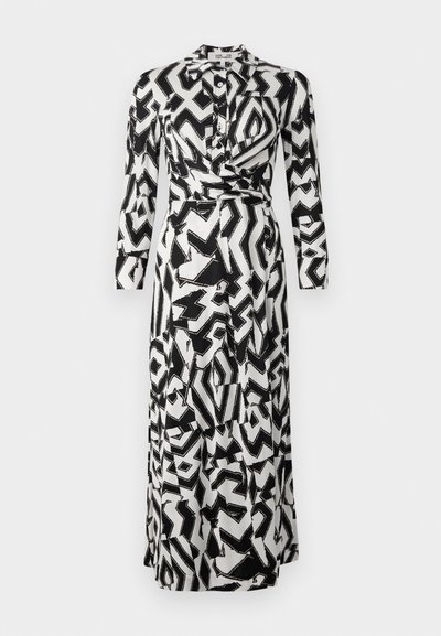 Lång klänning med ett svart och vitt abstrakt geometriskt mönster, tillverkad av lättare tyg med krage och långa ärmar.
