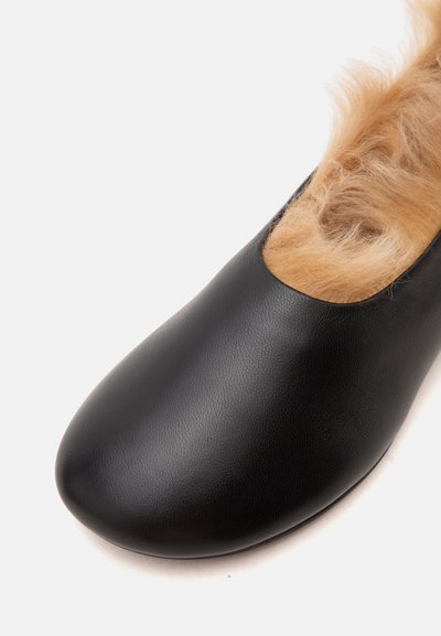 Chaussure en cuir noir avec bout arrondi et doublure en fourrure légère marron clair visible à l'ouverture, sur fond blanc.
