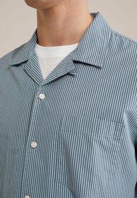Camicia button-up in cotone, con un motivo a righe blu chiaro e bianche, una tasca e un colletto classico.