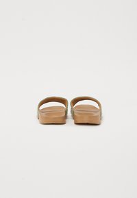 Brown platform sandals with green woven straps, open back design, flat sole, and textured footbed.