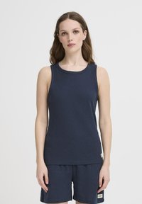 Canotta a coste blu navy con scollatura rotonda e armhole. Abbinata a pantaloni corti coordinati con un patch che presenta il logo del marchio.