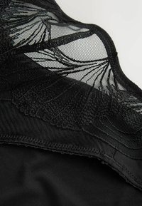 Black mesh lingerie featuring intricate lace detailing, smooth fabric, and a curved edge design. The texture combines sheer and opaque elements.