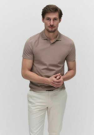 Beige polo skjorte med korte ærmer og krave, parret med lyse kremfarvede bukser. Simpelt design, glat tekstur, ingen synlige mønstre.
