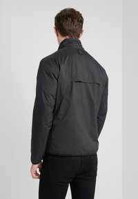 Černá péřová bunda s vysokým límcem, vybavená zadním klopou a texturovaným detailem. Vyrobena z hladkého, lehkého materiálu.