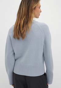 Maglione azzurro chiaro lavorato a maglia con orlo e maniche a coste, caratterizzato da un collo rotondo e sottili dettagli testurizzati.