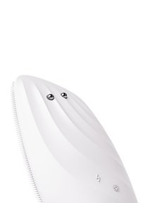 Dispositif de nettoyage facial en silicone blanc avec un design lisse et courbé, doté de deux boutons de contrôle argentés et d'un dos texturé pour une prise en main.