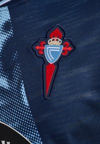 Dark blue jersey featuring an embroidered club crest with a red and blue design, accented by a crown and detailed stitching.