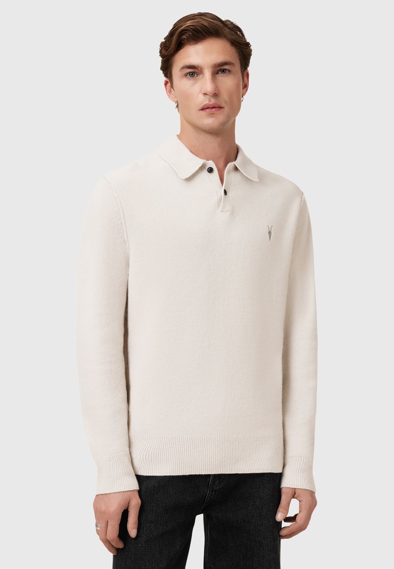 Krémově bílá polo košile s dlouhým rukávem vyrobená z měkké tkaniny, s límečkem, třemi knoflíčky a malým vyšitým logem.