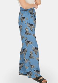 Jasnoniebieskie, szerokie spodnie z czarno-białym wzorem liści. Wykonane z gładkiego, lekkiego materiału z elastyczną talią.