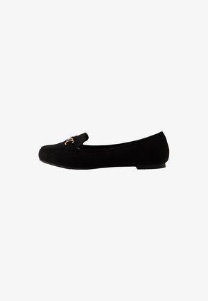 Zwarte suède platte schoenen hebben een ronde neus, een versierde band met gouden hardware en een lage hak. Soepele textuur en minimalistisch ontwerp.